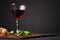 Prosciutto, fragrant green basil and peppercorns on the balck background. A glass of wine and a pile of cut cured on the