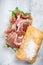 Prosciutto parma ham sandwich on ciabatta bread with arugula. White background. Top view