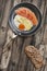 Prosciutto Rashers With Fried Egg In Frying Pan With Slice Of Brown Bread Set On Old Cracked Wooden Garden Table