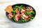 Prosciutto salad with olives in a black bowl. Spanish cuisine. Top view. Free space for your text.