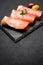 Proscuitto ham arranged in thinly sliced rolls on stone serving board