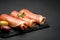 Proscuitto ham arranged in thinly sliced rolls on stone serving board