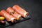 Proscuitto ham arranged in thinly sliced rolls on stone serving board