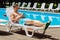 Prosperous businessman chilling while sunbathing near pool