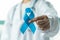 Prostate cancer blue awareness ribbon for men health in November with light blue bow color on medical doctorâ€™s hand in clinical