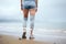 Prostheses on the legs of a young disabled woman. A woman stands on the seashore in cloudy weather with her back to the