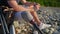 prosthetic leg of young adult man, sitting on shore of river after hiking