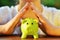 Protect your savings - with hands covering green piggy bank