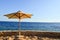 Protecting beautiful umbrellas made of yellow fabric from dried branches against the blue sky, on the shore of the salt sea at the