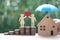 Protection,Love couple holding heart shape standing on stack of coins money with model house under the umbrella on natural green