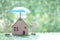 Protection,Love couple and model house under the umbrella on natural green background, Safe investment and save money for prepare