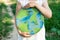 Protection and love of earth. Little girl holding planet in hands against green spring background. Earth day holiday concept.