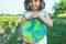 Protection and love of earth. Little girl holding planet in hands against green spring background. Earth day holiday concept.