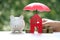 Protection, Model house and piggy bank with the umbrella on nature green background,Finance insurance and Safe investment concept
