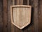 Protection shield shaped sign made of bright wood and hanging on ropes with wood planks background