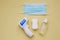 Protection during virus outbreak concept: surgical mask, soap, hand sanitizer and infrared thermometer on yellow background