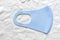 Protective blue face mask with white disposable vinyl gloves above white background. Infection prevention during lockdown