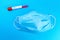 Protective face mask or medical mask with coronavirus tube test on blue background. Coronavirus or COVID-19 protection concept