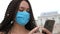 Protective face mask, smartphone and young adult woman