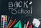 Protective mask and sanitizer, School supplies on blackboard background. Top view. Chalk inscription - Back to school