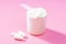 Protein scoop and capsules on pink background close-up