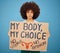 Protest, human rights and woman with a poster for abortion, body freedom and justice against a blue studio background