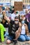 A protester wears a PPE Face Mask while kneeling on cobbles, saluting and holding a Black Lives Matter sign up high at a BLM