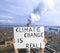 Protestor holding placard with text Climate Change Is Real and blurred view of industrial factory on background