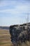 Protruding part of rock against cloudy sky and agricultural fields. Peaceful autumn rural landscape. Copy space.