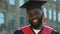 Proud afro-american student in hat and gown looking to camera and smiling