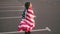 Proud american girl walking and wraping the american flag over her shoulders looking at the camera. Slowmotion shot