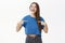 Proud attractive european female student in blue t-shirt with healthy long brown hair laughing joyfully and pointing