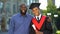 Proud glad father hugging graduating son with diploma, education degree, success