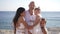 Proud happy Caucasian father standing with daughters on Mediterranean sea coast looking at camera smiling. Confident man