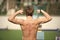 Proud of his shape. Man athlete training outdoor shows his muscular back. Athletic man posing with muscles. Athlete