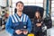 Proud mechanic, posing in front of a client with her car