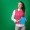 Proud student woman with blue notebook against green background