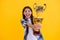 proud teen girl with champion cup award, selective focus. teen girl hold her award champion cup isolated on yellow. teen