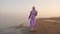 Proud woman approaches easel with bright seascape on beach