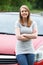 Proud Young Female Driver Standing In Front Of Car