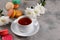 Provence breakfast. Bright french macarons on a round plate, a cup of tea, a teapot. Grey background