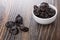 Prunes in bowl, scattered on wooden table
