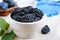 Prunes in a clay bowl and fresh plums, leaves on a table.