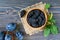 Prunes in a clay bowl and fresh plums, leaves on a wooden table.