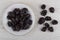 Prunes in plate, scattered on wooden table. Top view