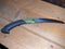 Pruning saw with green handle on wooden background