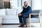 Psychologist, waiting and black man sitting on chair at work, job or modern workplace in modern office lounge. Portrait