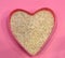 Psyllium in the shape of a heart on a pink background, top view. Super food psyllium seeds, keto diet ingredient