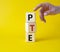 PTE - Pearson Tests of English symbol. Wooden cubes with word PTE. Businessman hand. Beautiful yellow background. Business and PTE