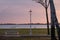 Public bench and streetlamp in front of Palic Lake in Subotica, Serbia, with a green lawn in the foreground, during sunset.